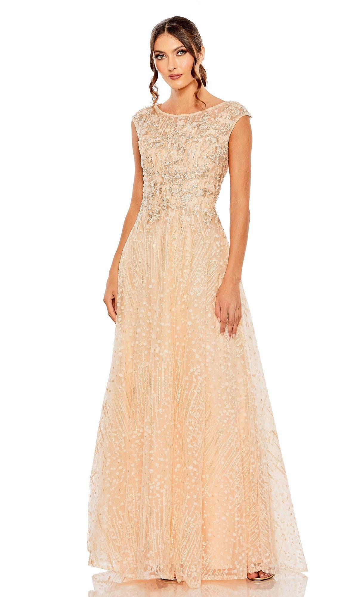 A woman models the Mac Duggal 20501, a floor-length, sleeveless peach formal dress featuring intricate beadwork and a delicate lace overlay, posed against a white background.